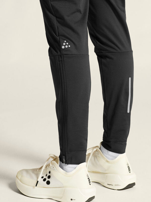 Black athletic pants with white sneakers on a light gray background