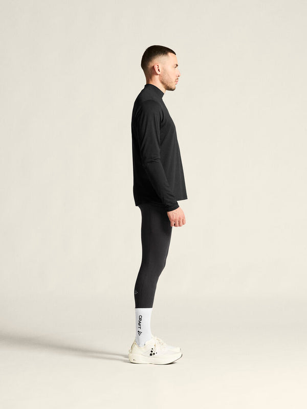 Man wearing a black outfit with white socks and shoes on a plain background