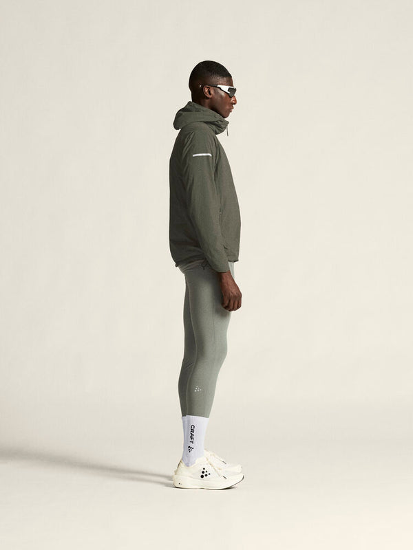 Person wearing a green tracksuit and white sneakers on a light gray background