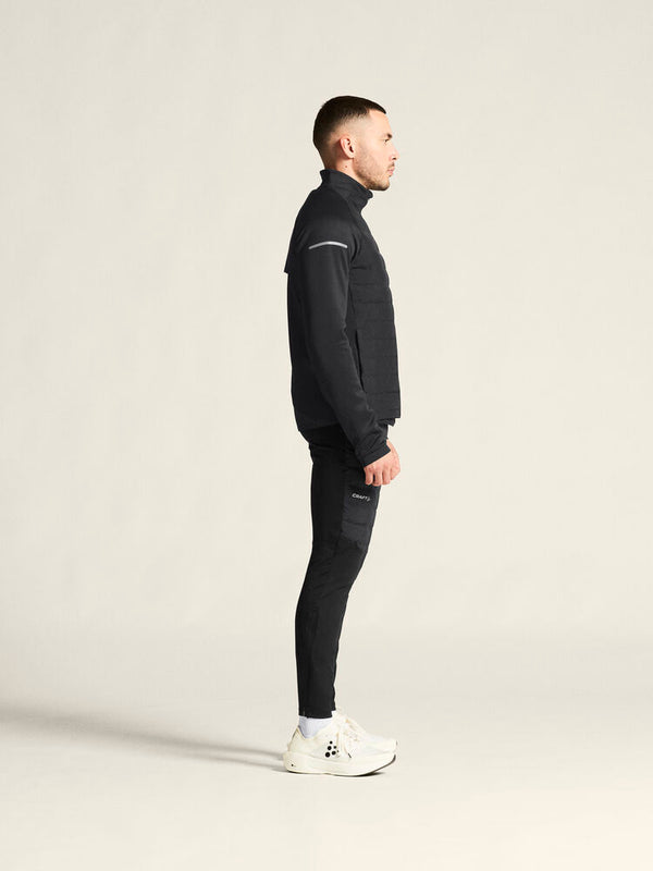 Man wearing a black tracksuit with white sneakers on a light gray background