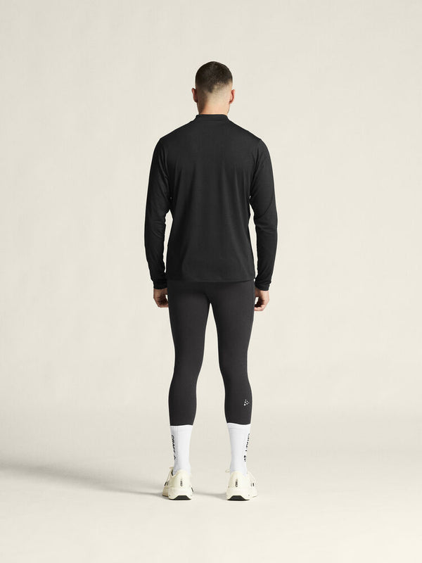 Person wearing a black long-sleeve top and leggings on a beige background