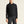 Person wearing a black pullover with a brand logo on a beige background