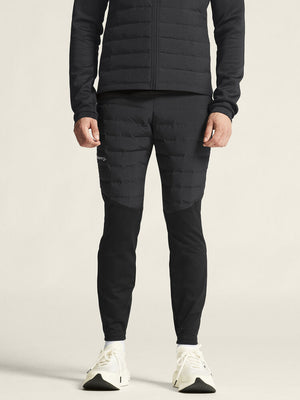 Person wearing a black puffer jacket and pants on a light background