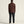 Person wearing a brown hoodie and dark pants on a beige background