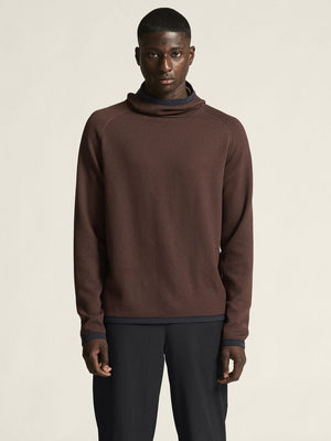 Man wearing a brown ribbed sweater against a beige background