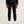 Person wearing black pants and a black jacket on a beige background
