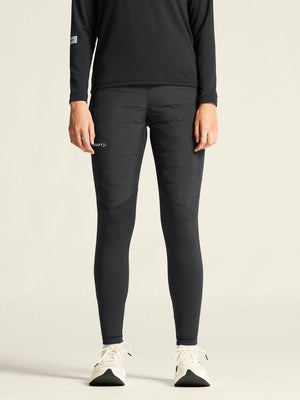 Person wearing black athletic leggings and a black long-sleeve shirt on a beige background