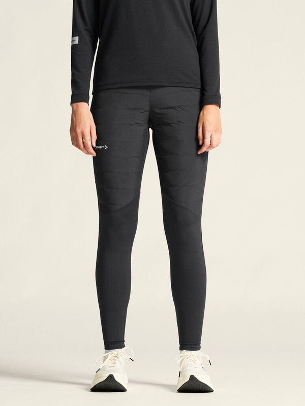 Person wearing black athletic leggings and a black long-sleeve shirt on a beige background