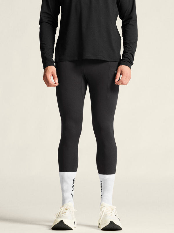 Person wearing black long-sleeve top, black leggings, and white socks with a brand logo on a beige background