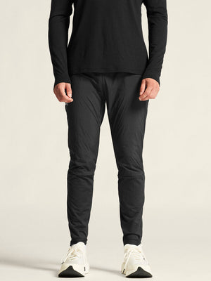 Person wearing a black long-sleeve top and black pants on a light gray background