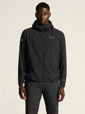 Person wearing a black jacket with a brand logo on a beige background