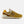 A New Balance 574 sneaker in a mustard yellow and brown colorway, featuring a cream midsole and white trim, shown from a side profile on a light gray background.