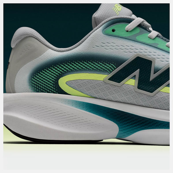 Gray and green athletic shoe with brand logo on a dark background