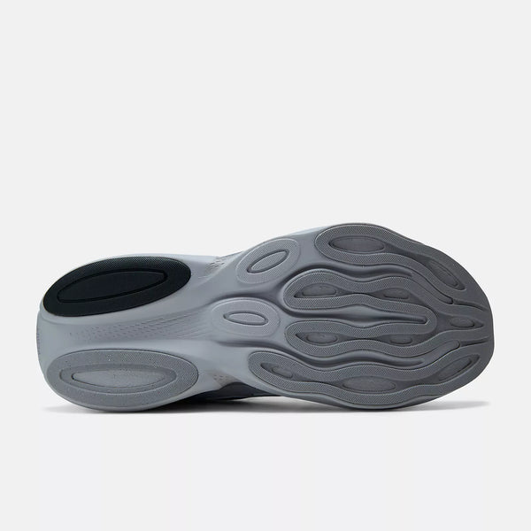 A close-up of a sneaker's sole showing its textured, wavy gray rubber design with a black heel accent, photographed on a light gray background.