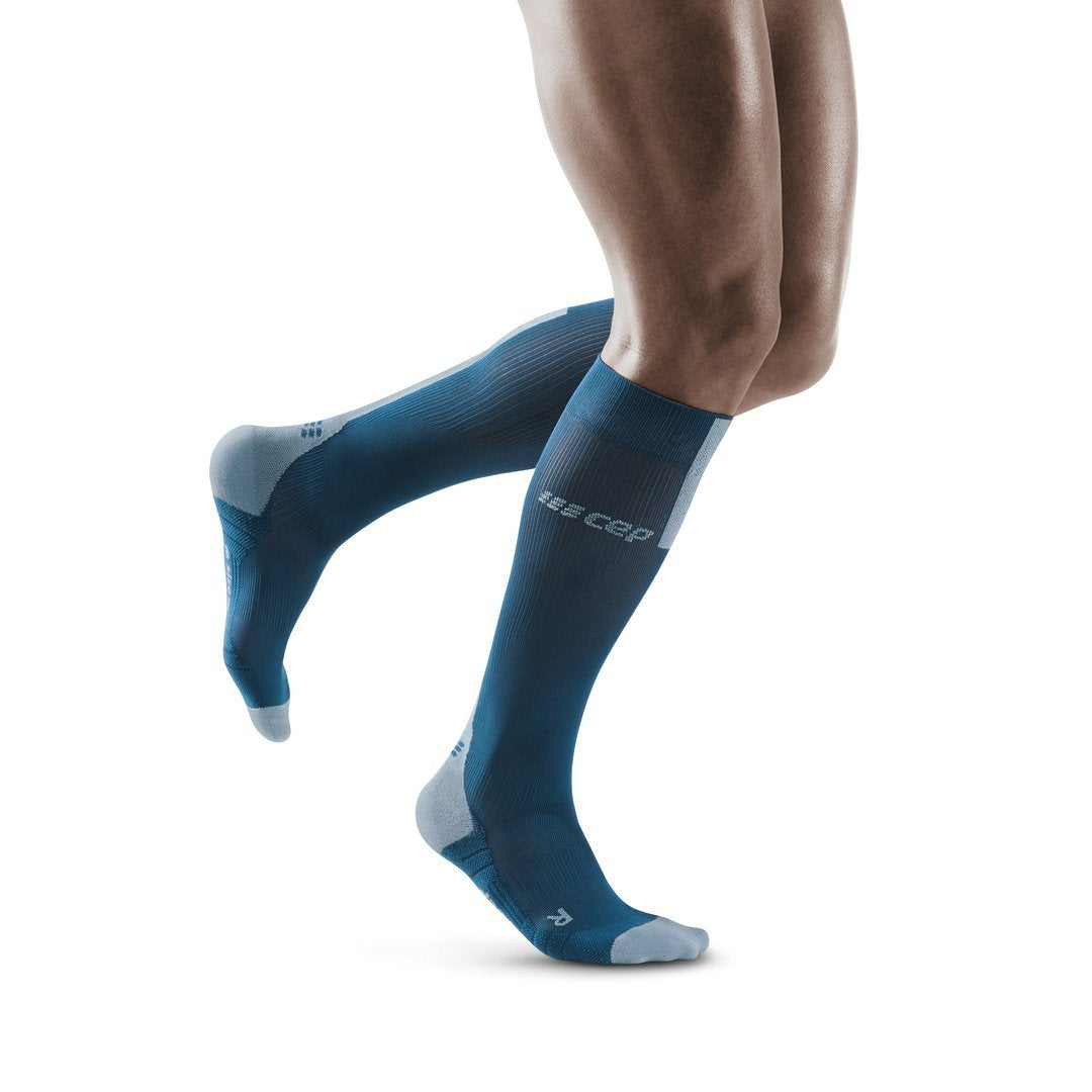 Right side view of a model wearing the CEP Tall Compression Socks in the color Blue/Grey
