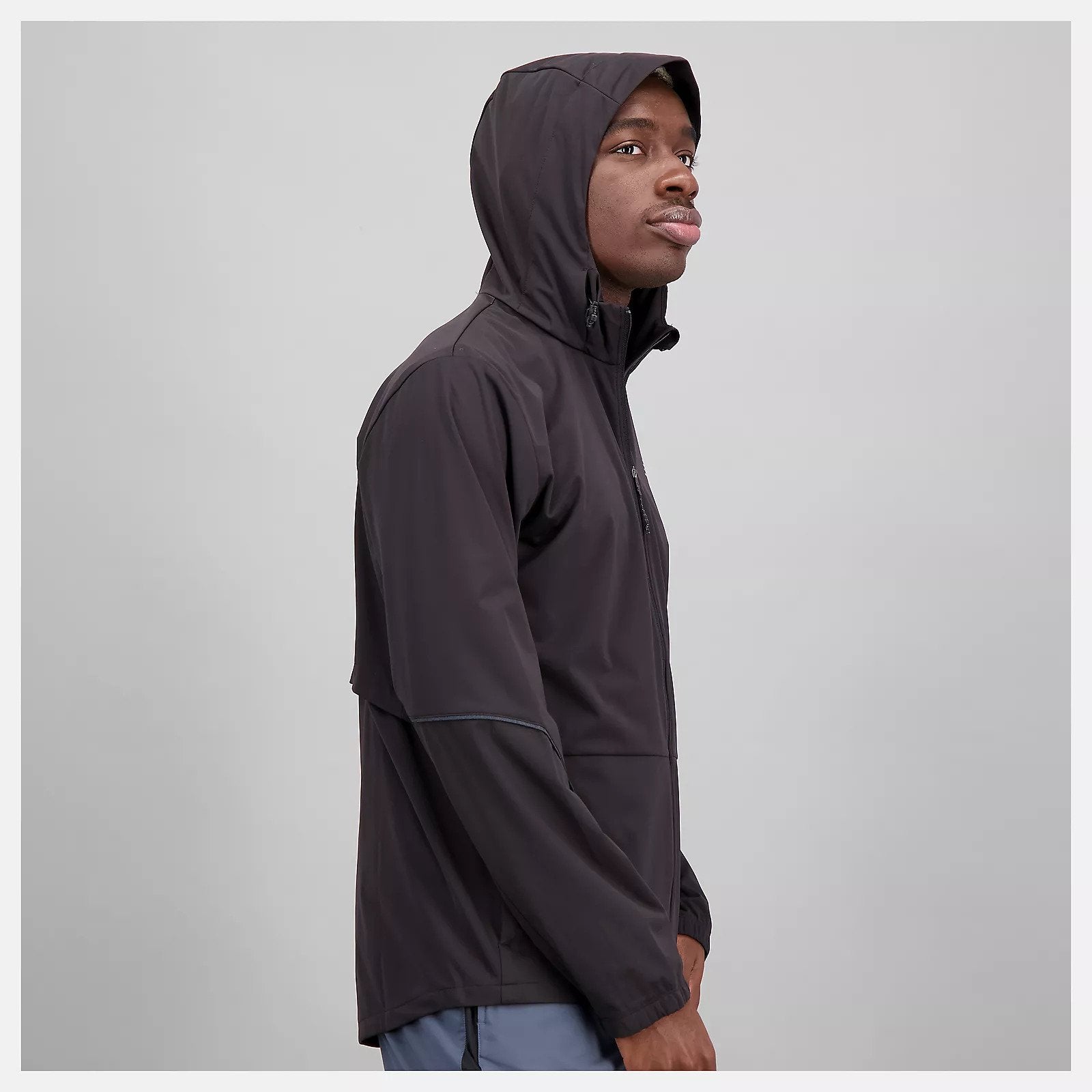 Side view of a model wearing the Men's Impact Run Water Defy Jacket by New Balance in Black